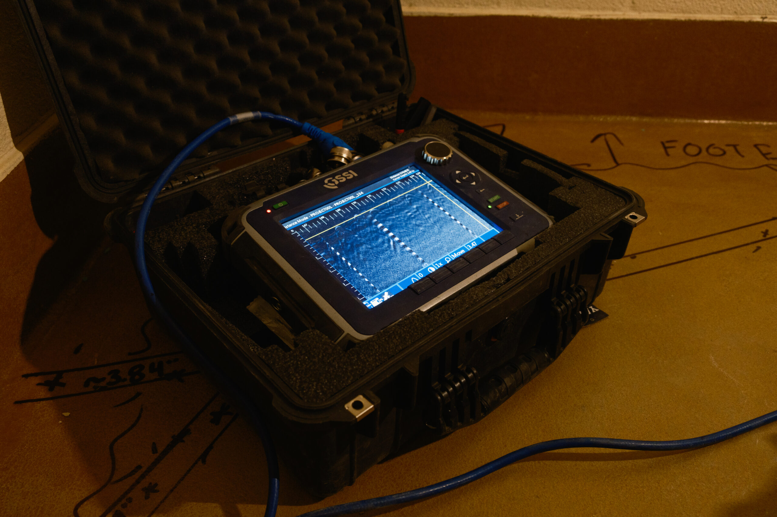 Safe Site-386 Close-up of a GSSI ground-penetrating radar control unit in a protective case, displaying scan data on its screen.